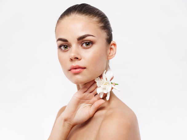 pretty woman naked shoulders white flower cosmetics light background - Photo, Image