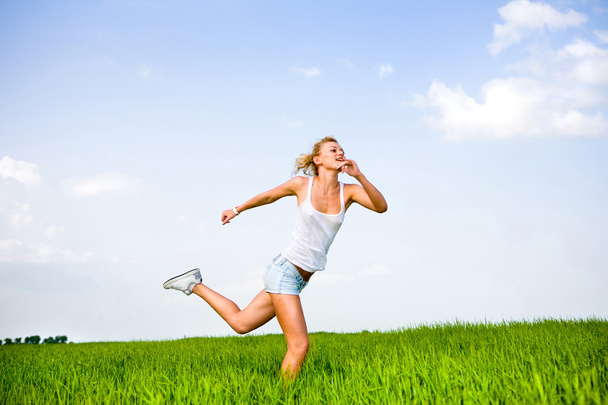 Happy young woman is running in a field - Photo, image