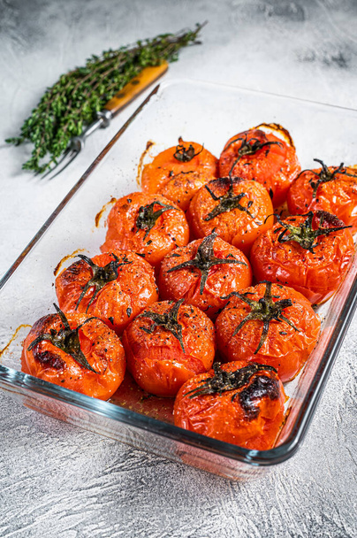 Paahdettuja tomaatteja oliiviöljyn ja timjamin kanssa paistoastiassa. Valkoinen tausta. Yläkuva - Valokuva, kuva