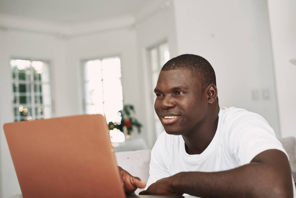 uomo aspetto africano a casa davanti al sorriso di intrattenimento del computer portatile - Foto, immagini