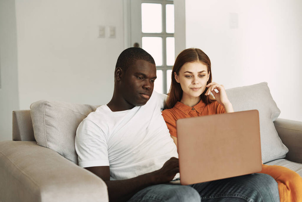 young couple at home on the couch in front of a laptop vacation internet - Photo, Image