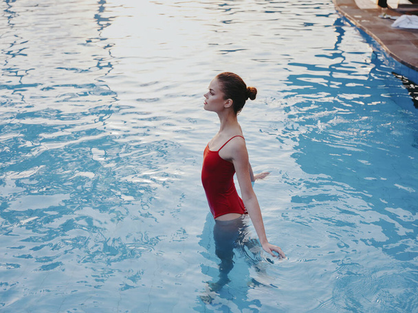 Frau in rotem Badeanzug schwimmt in transparentem Pool-Wasser Seitenansicht Modell - Foto, Bild