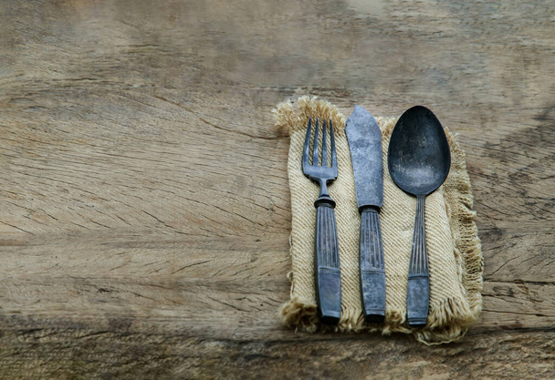Rustic ancient vintage cutlery in a sackcloth on rustic wooden table. Copy space, Selective focus. - Photo, Image