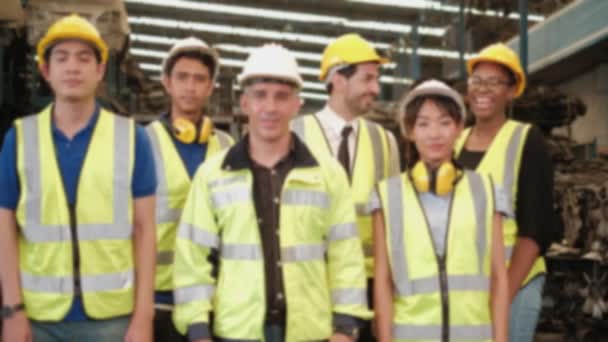 Blur focus VDO: Ομάδα μηχανικών με στολές και κράνη σταυρώνουν τα χέρια και γελάνε ευτυχισμένοι. Όλοι οι συνάδελφοι είναι επαγγελματική ομαδική εργασία στο εργοστάσιο αποθήκευσης ανταλλακτικών μηχανημάτων. - Πλάνα, βίντεο