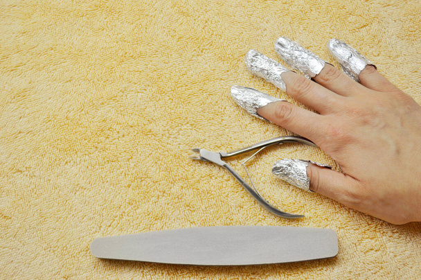 Removing shellac from nails. fingers with foil, nail file and wire cutters - Photo, Image