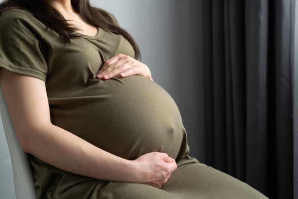 健康的な妊娠。腹の大きい妊婦さんが手にしている様子を横から眺めます。お母さん待ってる赤ちゃん - 写真・画像