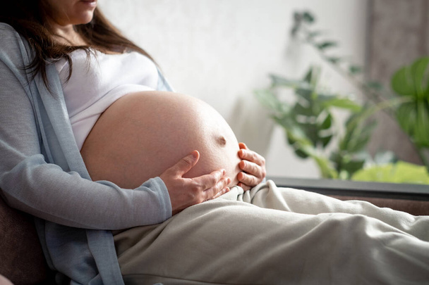 terhes nő nagy has előrehaladott terhesség pihen kanapén otthon. Egészséges terhesség és boldog moterinty - Fotó, kép