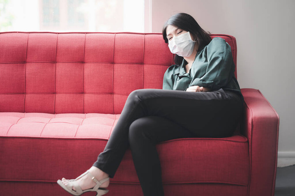 Mulher asiática com máscara protetora dormindo no sofá sentindo-se cansada e doente  - Foto, Imagem