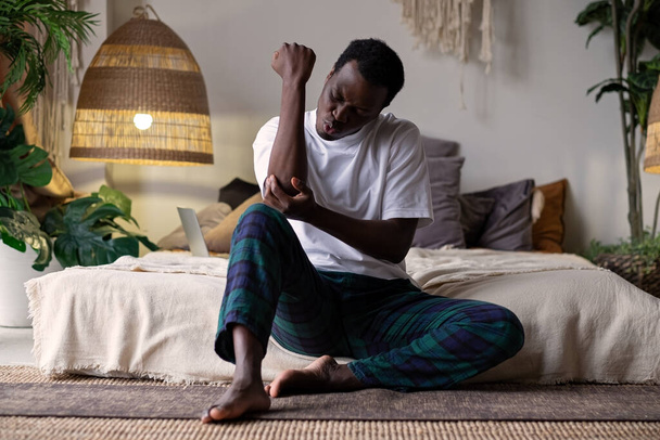 Africain malheureux souffrant de douleur au coude à la maison - Photo, image