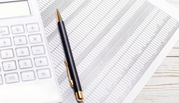 On a light wooden table lie reports, a white calculator, and a pen. Business concept - Photo, image