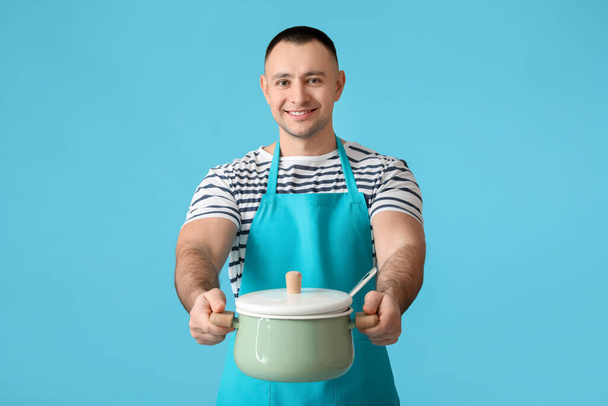 Young man with cooking pot on color background - Photo, Image
