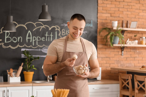 Young man with mushrooms in kitchen - Foto, Imagen