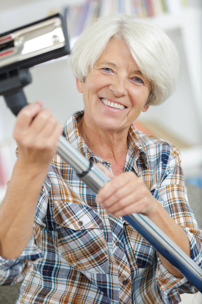 happy senior woman before vacuum cleaning house - Foto, Bild