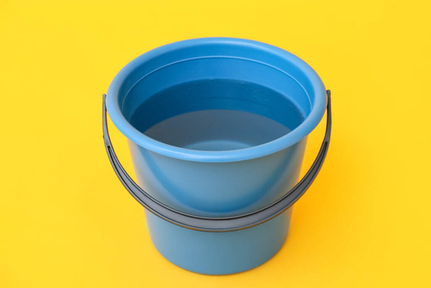 Plastic bucket with water on color background - Фото, зображення