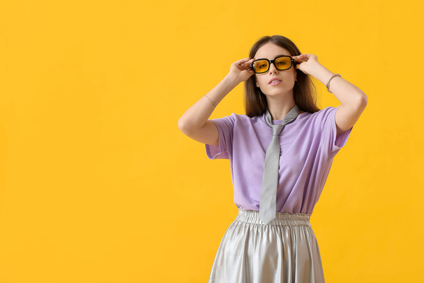 Красивая молодая женщина в стильных солнечных очках на цветном фоне - Фото, изображение