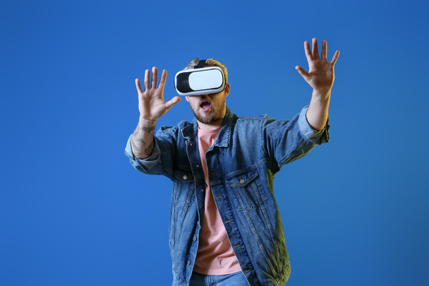 Young man with VR glasses on color background - Foto, Imagem