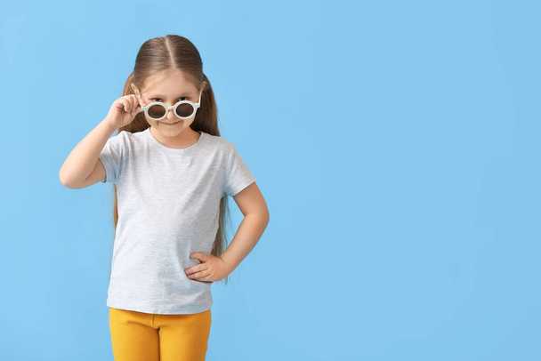 Cute little girl wearing stylish sunglasses on color background - Foto, Imagen