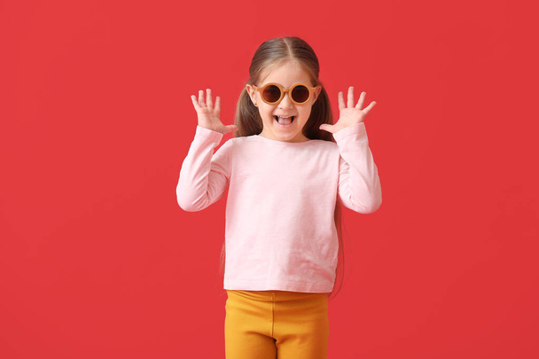 Cute little girl wearing stylish sunglasses on color background - Фото, зображення