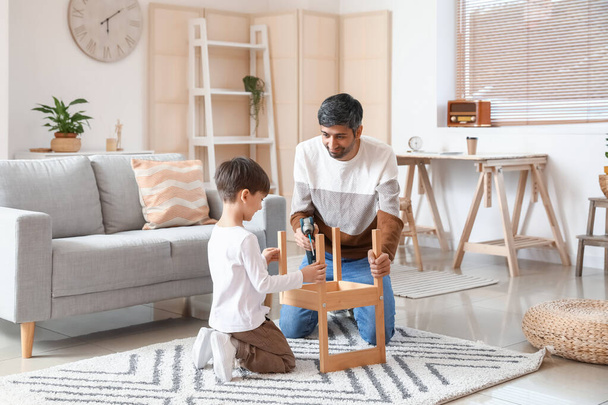 Vater und kleiner Sohn reparieren Stuhl zu Hause - Foto, Bild
