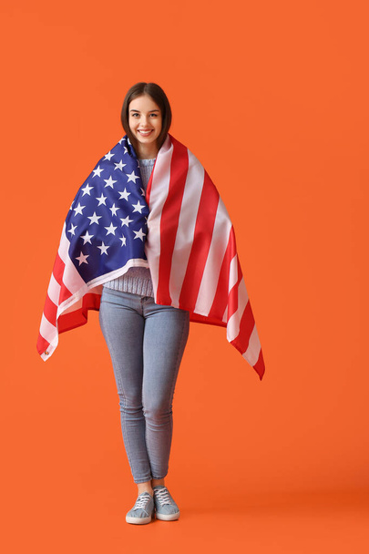 Beautiful young woman with USA flag on color background - Foto, Bild