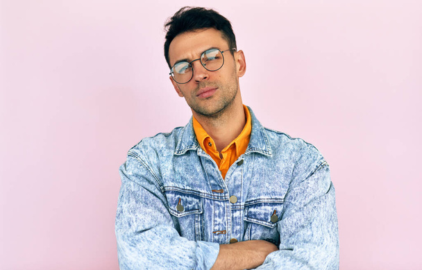 Studio of a handsome pensive young man thinking an idea posing over isolated pink background. Male wearing stylish casual clothes, transparent eyeglasses has confuse expression. - Fotografie, Obrázek