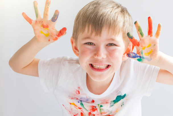 Portrait of joyful cute preschooler little boy 5-6 years with colorful painted hands. Smiley hands. Finger drawing, education and child development. Happy childhood. - Photo, Image