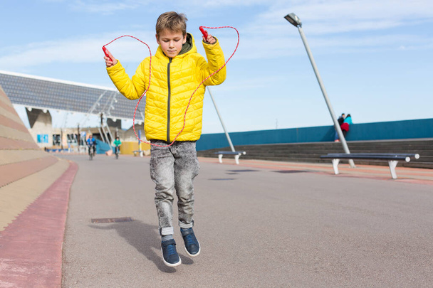 Stylish young boy, teenager is jumping with skipping rope, outdoors - Photo, Image