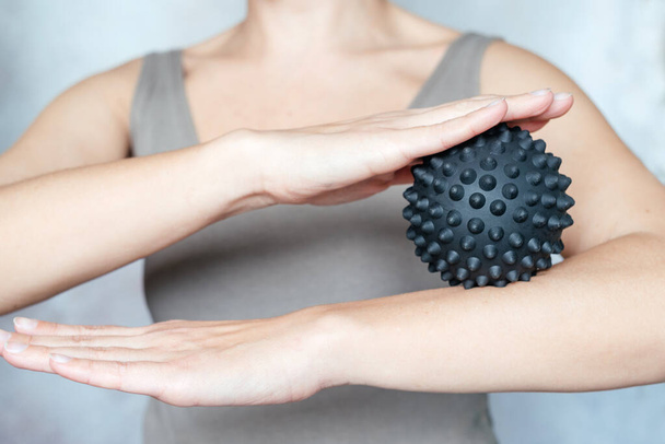 Женщина держит колючий триггерный массажный шар, используемый для лечения мышечной боли и массажа глубоких тканей, физиотерапии и остеопатии. - Фото, изображение