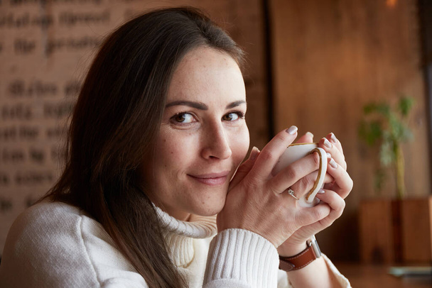 Χαλαρή λευκή γυναίκα πίνει τσάι ή καφέ. Απολαμβάνοντας το χρόνο στην καφετέρια - Φωτογραφία, εικόνα