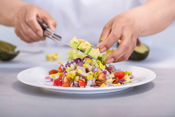 Avocadowürfel auf einen leckeren Salat legen - Foto, Bild