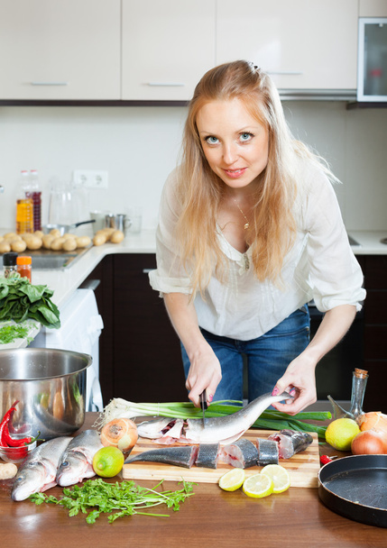 Blonde woman cutting raw fish  - Foto, Bild