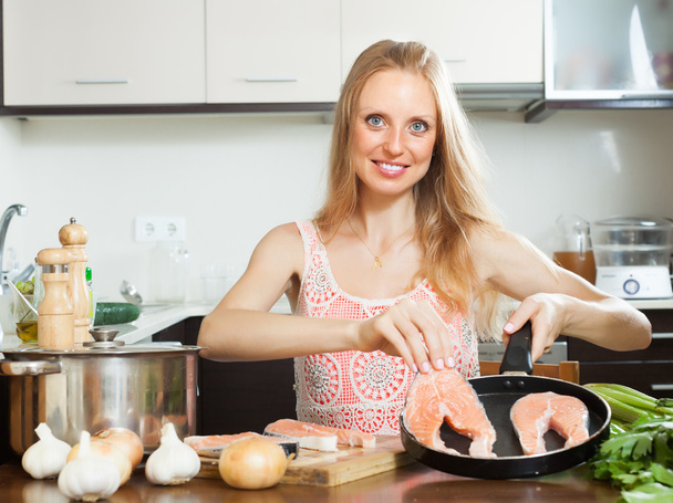Positive housewife cooking raw salmon  - Фото, зображення