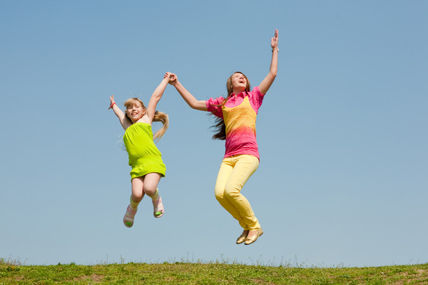 Two girls jumping on green meadow - Photo, Image