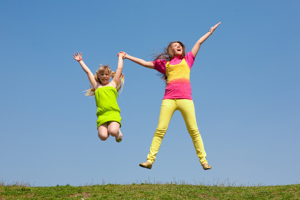 zwei Mädchen springen auf grüne Wiese - Foto, Bild