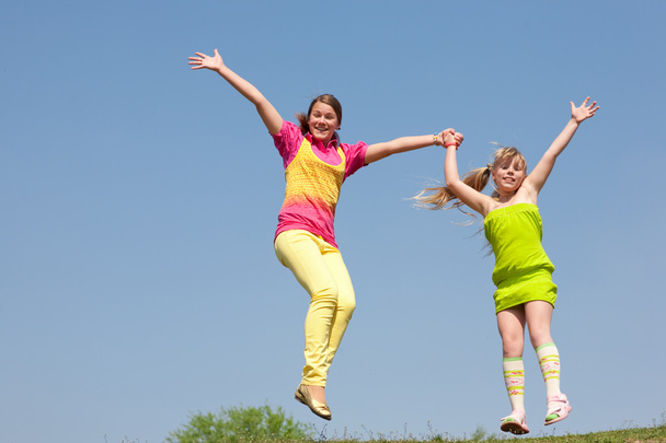 Deux filles sautant sur la prairie verte
 - Photo, image