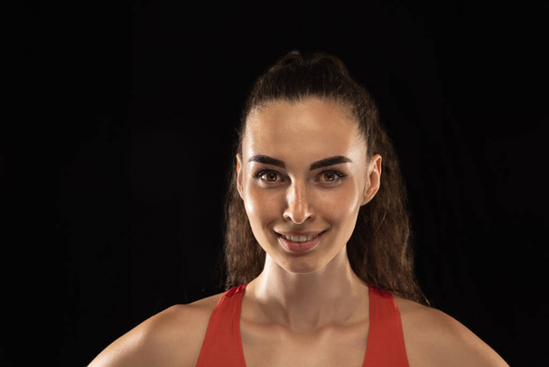 Close-up portrait of young girl female athlete isolated over dark background. - Valokuva, kuva