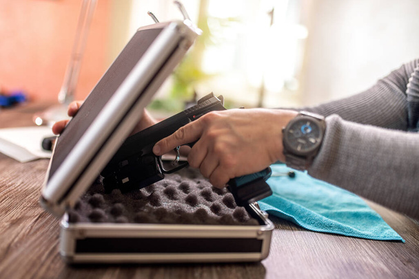 Man putting gun in safe box at home. - Foto, Imagen