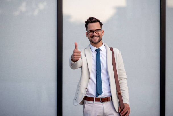 Portrait of young businessman ,standing outdoor and showing thumbs up. - Photo, Image
