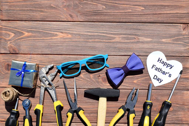 Kompozycja z narzędziami, muszką, okularami, pudełkiem na drewnianym tle. Szczęśliwego Dnia Ojca - Zdjęcie, obraz
