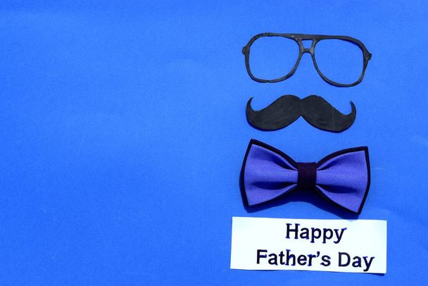 Glasses and bow tie on a blue background. Happy Father's Day - Photo, Image