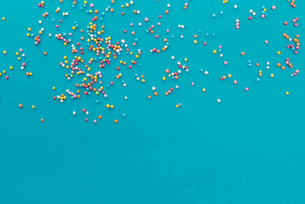 Colorful sugar sprinkles on blue background. Festive backdrop - Foto, Imagen