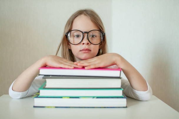Little girl with glasses does homework, reads books. - Фото, изображение