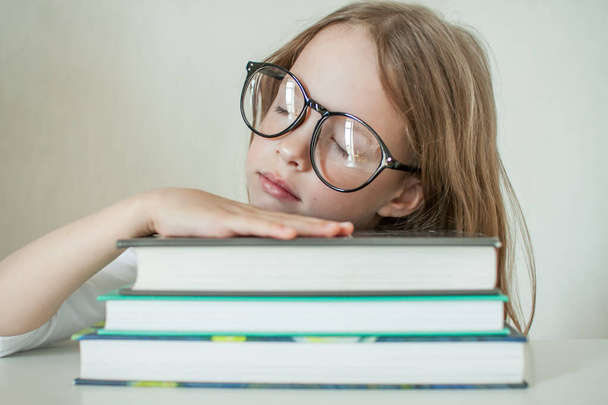 Little girl with glasses does homework, reads books. - Foto, afbeelding