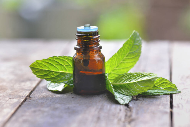 mint leaf with a bottle of aromatic oil on a wooden table  - Photo, Image