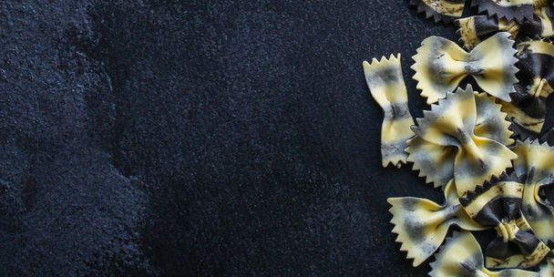 Draufsicht auf rohe rohe Pasta auf schwarzem Hintergrund - Foto, Bild