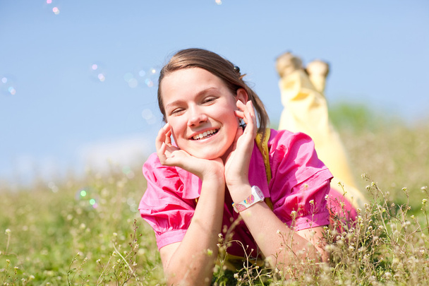 Досить усміхнена дівчина розслабляється на зеленому лузі, повній квітів. Отже
 - Фото, зображення