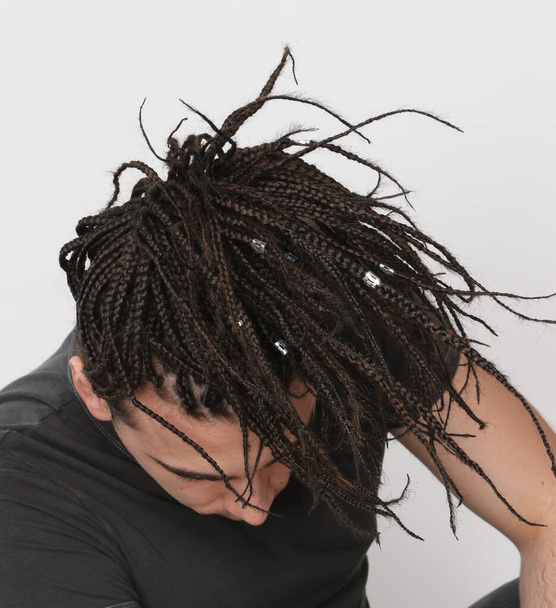 Stylisches männliches Model mit Afro-Zöpfen posiert im Studio auf isoliertem Hintergrund. Stil, Trends, Modekonzept. - Foto, Bild