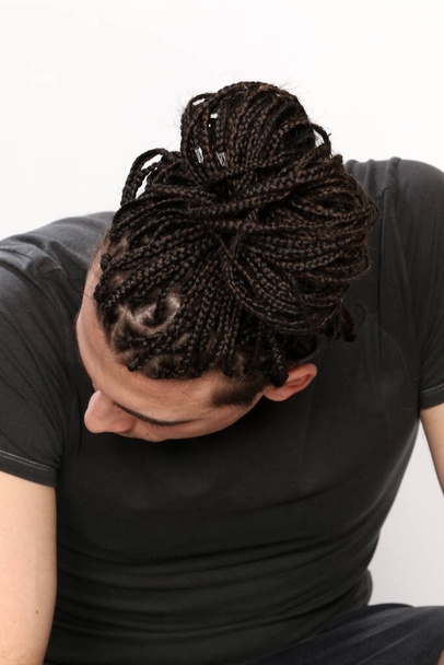 Стильна чоловіча модель з афро косами позує в студії на ізольованому фоні. Стиль, тенденції, концепція моди
. - Фото, зображення