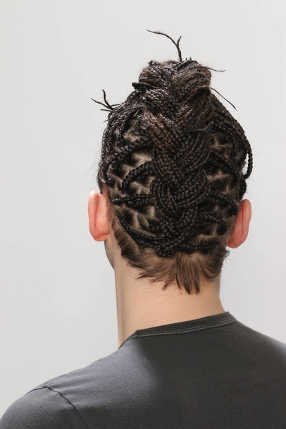 Stylish male model with afro braids posing in studio on isolated background. Style, trends, fashion concept. - Φωτογραφία, εικόνα