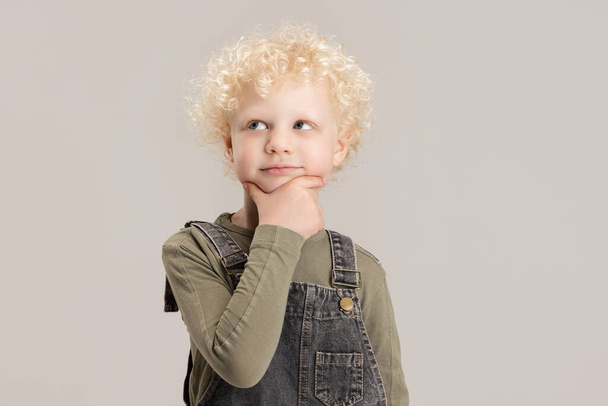 Un petit garçon caucasien posant isolé sur fond de studio gris. - Photo, image